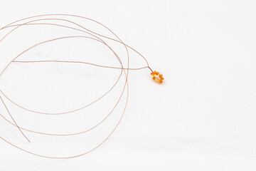 Wire and some golden or amber colored beads and loops on white background. Handmade, making of jewelry, decorative elements, leisure, hobby, female accessories concept.