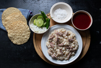 Pozole seco, typical food from colima Mexico accompanied by lemon, onion, green chili, sauce, salt...