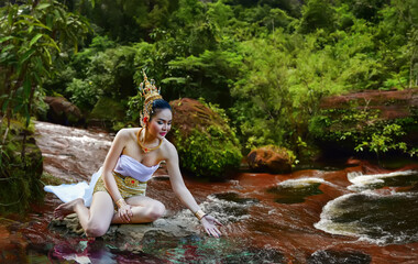 Beautiful woman wearing traditional thai dress with thai style in beautiful water fall in neture.