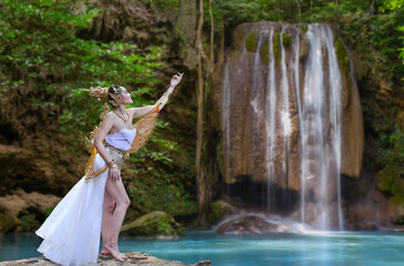 Beautiful woman wearing traditional thai dress with thai style in beautiful water fall in neture.