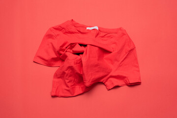 A red t-shirt on a red flat lay background.