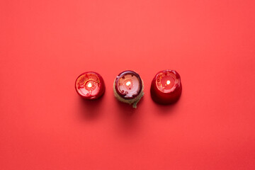 Red burning candles on the red flat lay background.