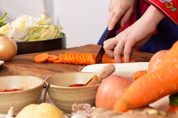 close up hand woman wearing hanbok cutting vegetable with knife on table preparing cook kimchi traditional food in kitchen copy space