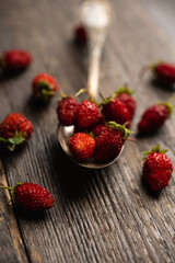 Red ripe wild strawberry in old vintage spoon on the rustic background. Selective focus. Shallow depth of field.
