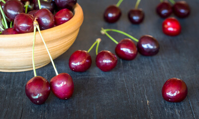 Fresh cherry berries in a light clay bowl on a dark rustic wooden background