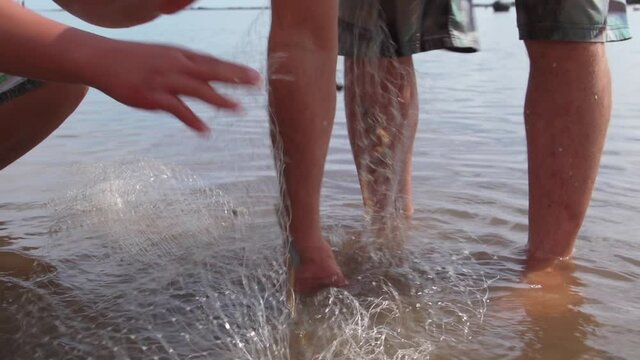 Two men retrieve small fish in fish net in a fish pond in Molokai Hawaii. 