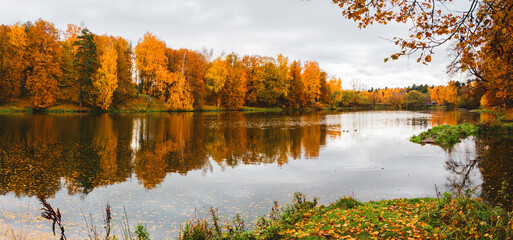 Late autumn nature landscape.Beautiful scene with forest lake and reflection on water surface.Trees with orange fall foliage.Cloudy autumn rainy morning.Calm weather.October scene.