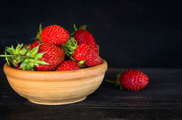 light clay Cup with red juicy strawberries on a wooden background with a copy of the space