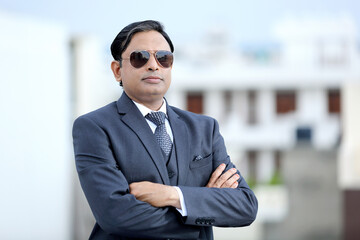 Young Indian confident businessman wearing suit and sunglasses standing outdoors.Young urban professional looking confidently into viewers eyes.