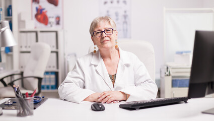 Obraz na płótnie Canvas Confident senior female doctor wearing glasses in hospital cabinet.