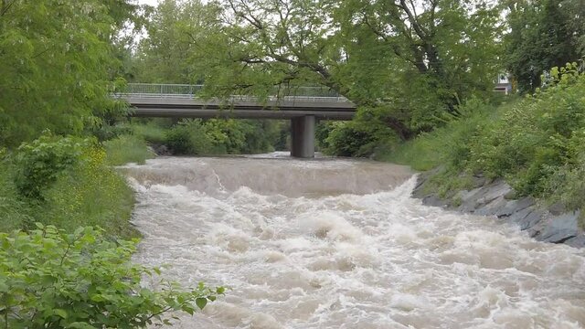 Slow motion of a muddy highwater river with a bridge, crane movement up