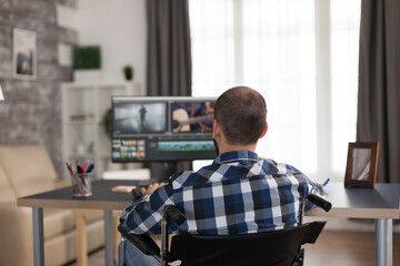 Videographer with headphones and moving handicap sitting on wheelchair working on movie. Invalid...