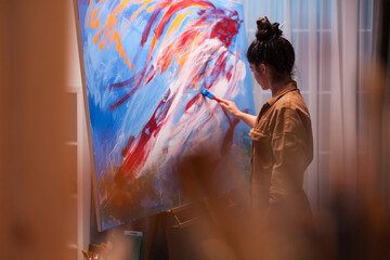 Woman with imagination painting a masterpiece in art workshop. Modern artwork paint on canvas,...