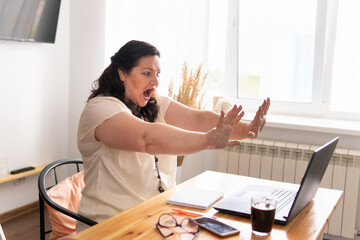 A woman sits at home at a desk, works with a laptop in social networks.