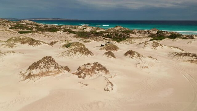 4WD car driving across sand dunes on the coast, Australia, aerial view