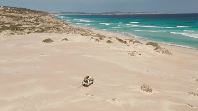 Jeep 4WD skidding fast on the sand on the Australian beach. Aerial view