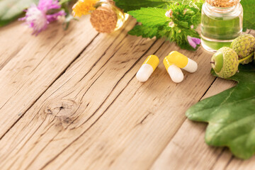 Various plants, leaves of healing herbs, capsules and healthy oils on wooden background with copy space. Alternative medicine or medical cosmetics concept