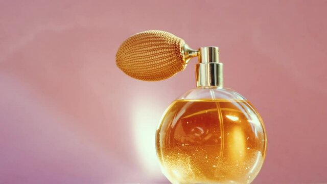 Luxury golden perfume bottle and shining light flares on pink background, glamorous fragrance scent as perfumery product for cosmetic and beauty brand, stock footage