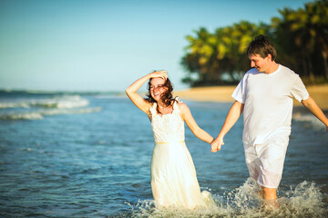 Fototapeta na wymiar couple in white clothes in water on beach. 