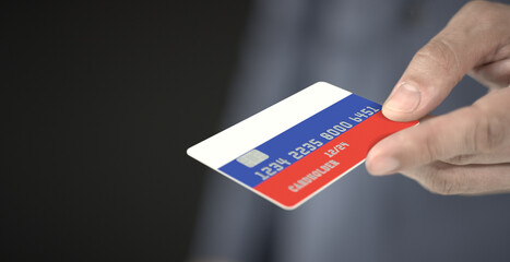 Man gives plastic bank card with printed flag of Russia. Fictional numbers