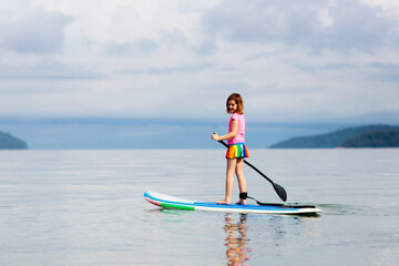 Child on stand up paddle. Water and beach sport