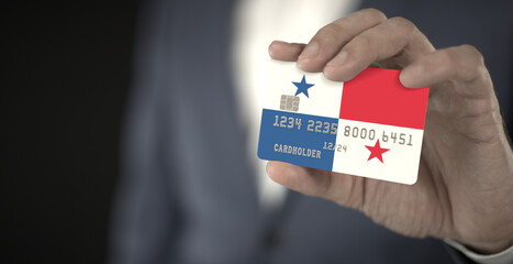 Businessman holding plastic bank card with printed flag of Panama in his hands, fictional numbers
