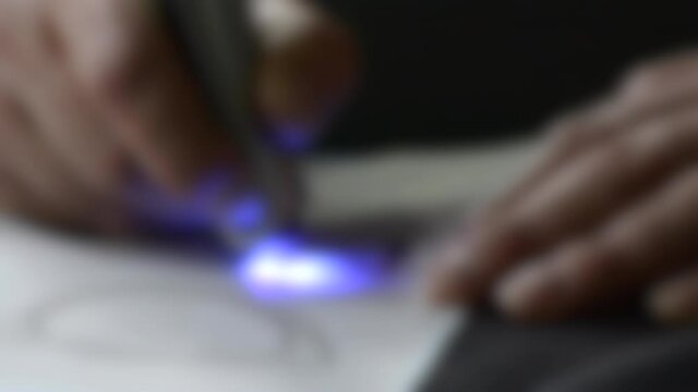 Blurred background. Drawing 3d pen draws with hardening photopolymer close-up.
