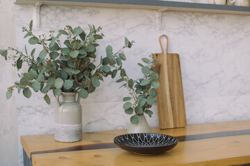 Bunches of eucalyptus in vases on wooden kitchen worktop. Still life shot of kitchen decor.