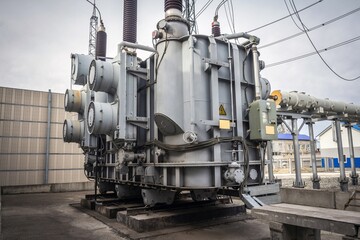 Big transformer at electric power station and worker in red helmet near it. Industrial concept.
