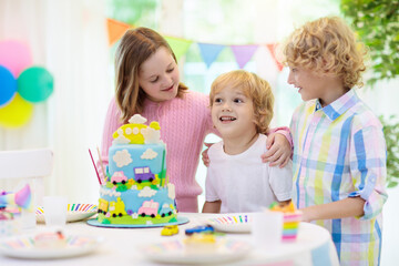 Fototapeta premium Kids birthday party. Child blowing out cake candle