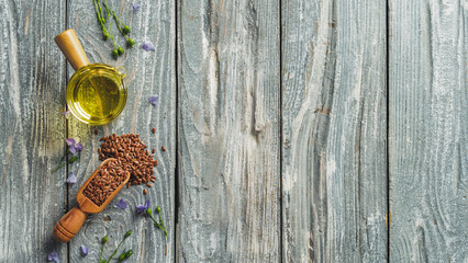 Flax seeds and flax oil. Brown linen seeds and flaxseed oil on old gray wooden background. Copy space. Top view or flat lay.