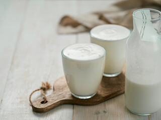 Kefir, buttermilk or yogurt with probiotics. Yogurt in glass on white wooden background. Probiotic...