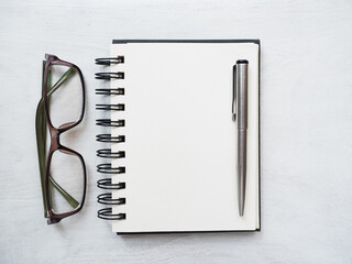 Blank notepad page, pen and glasses. Greeting card. Close-up, view from above, wooden surface. Concept of preparation for a professional holiday. Congratulations for relatives, friends and colleagues