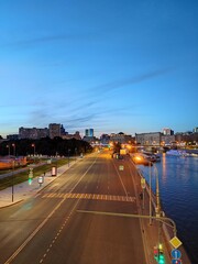 Top view of the empty road at night city Moscow, Russia. Pedestrians walk along the sidewalk. The road near the river with ships.