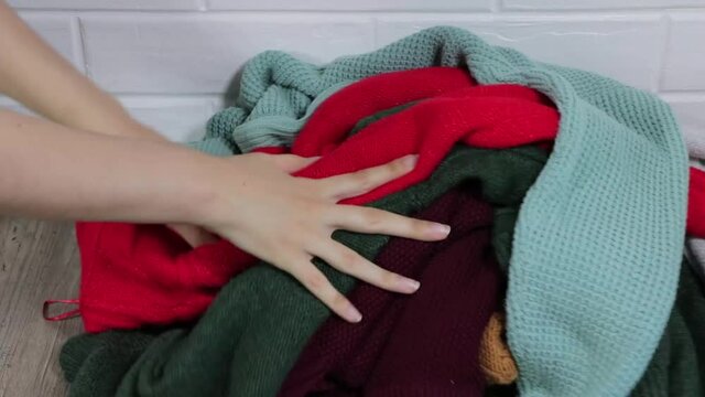 Sort the clothes. Throw clothes in a pile. A basic wardrobe. Minimalism. Clean up the closet. A mess. Women's clothing. Dirty laundry concept. A pile of clothes is on the floor. Clothes for donation.