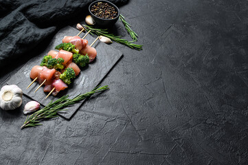 fresh raw chicken pieces on skewers. Black background. Top view. Space for text