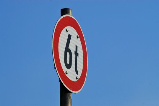 Traffic sign 6t white with red edge in front of blue sky asbackground