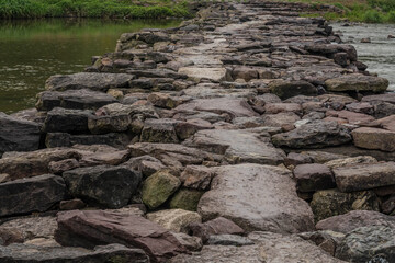 Man made stone bridge over rapidly flowing river.