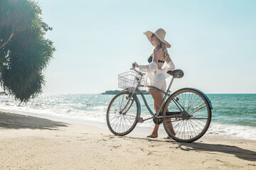 Fototapeta premium Happiness woman traveler with her bicycle rides on sea coastline