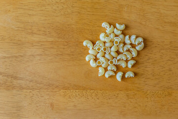 raw macaroni in bowl on wooden background