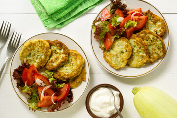 Zucchini fritters with tomato salad on a white background