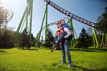 Man and woman happiness together in amusement park at American roller coaster attraction background. 