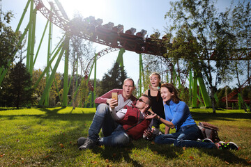 Group of people happiness together in amusement park at American roller coaster attraction...