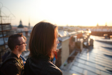 man and woman siting on rooftops historic center St. Petersburg and enjoying with  amazing sunset.