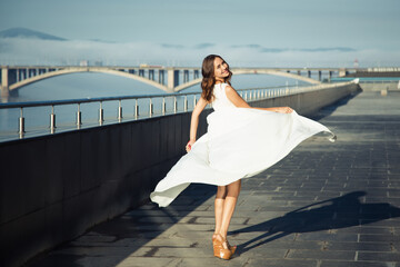 Beautiful fashion woman in a long white dress. Urban environment
