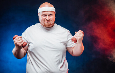 Burly man in a white tracksuit holds dumbbells in his hands and very tensely looks directly at the camera
