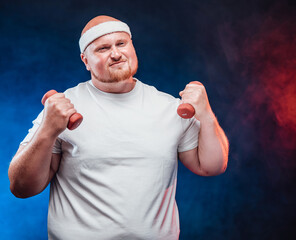 A very fat man in a white T-shirt with two dumbbells in each hand, on the contrast blue and red background