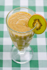 One tropical mixed drink, kiwi fruit cocktail served on green plaid tablecloth. Summer seasonal drink.