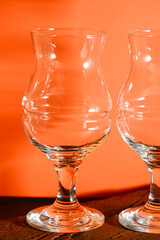 Two empty beer glasses over orange background.