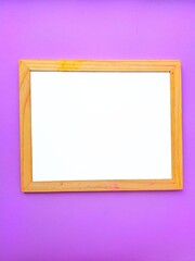 White empty clean school board on a purple background with a wooden brown frame. Back to school. Mockup.